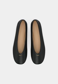 Ballerine nere con un esterno in pelle liscia, punta arrotondata e tacco basso, caratterizzate da un sottile logo dorato sul davanti.