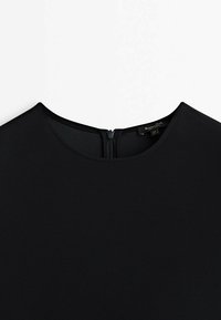 Robe noire avec encolure ronde et fermeture éclair au dos, présentée à plat sur un fond blanc.
