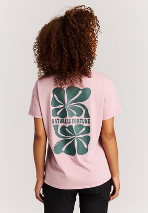 Lichtroze katoenen T-shirt met een grote groene afbeelding van gestileerde bladeren en de tekst "NATURE IS FORTUNE" op de achterkant.