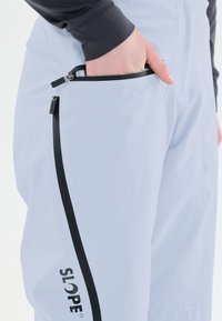 Ljusblå skidbyxor med en svart dragkedja och SLOPE-logotyp. Slät, vattenavvisande tyg med en avsmalnande passform.