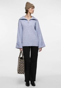 Svetlo purpurni rebrasti pulover s zip ovratnikom, uparen s crnim hlačama i karo torbom. Model nosi smeđu pletenu kapu.