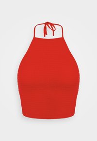 Top halter rosso in tessuto testurizzato, con design aderente, schiena aperta e magri laccetti al collo. Nessun ulteriore motivo o dettaglio hardware.