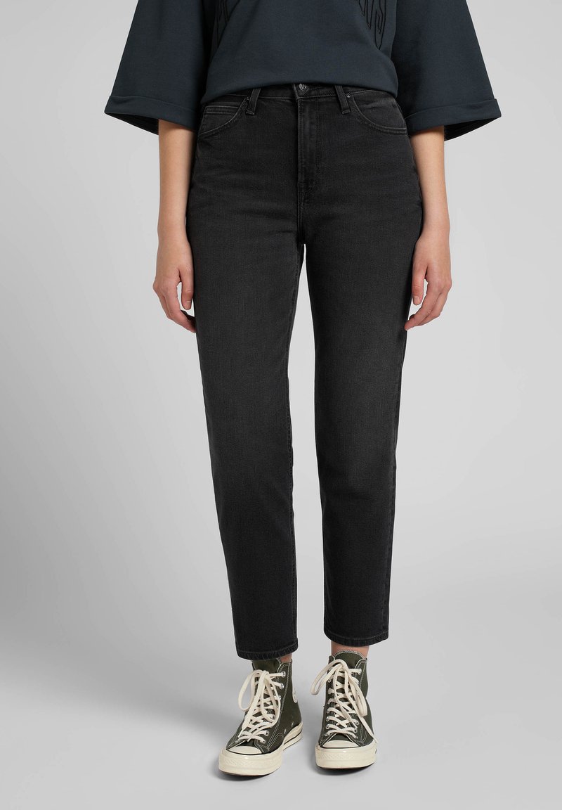 Black high-waisted jeans with a straight fit, four pockets, and a zip fly. Paired with green canvas high-top sneakers.