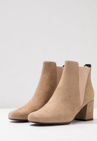 Beige mockask ankle stövlar med blockklack, med elastiska sidopaneler och en slät, mattyta. Klassisk design med rund tå.