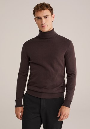 Suéter marrón de cuello alto en tejido de punto ligero, con mangas largas y puños y dobladillo acanalados, combinado con pantalones oscuros.