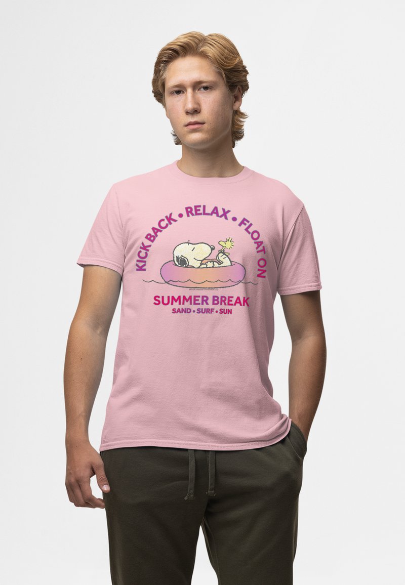Joven con una camiseta rosa con Snoopy flotando en un flotador y texto "Kick Back, Relax, Float On, Summer Break, Sand, Surf, Sun."