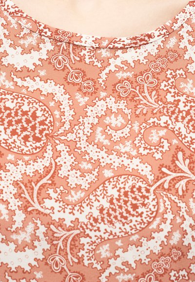 Ύφασμα κοραλλί και λευκό με αφηρημένο σχέδιο παϊρέ, που περιλαμβάνει λουλουδένια και φυλλώδη μοτίβα.