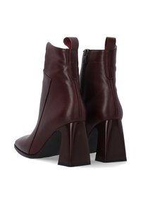 Bottines en cuir bourgogne avec un bout pointu, dotées d'un talon bloc et d'une fermeture éclair sur le côté, texture lisse avec un design épuré.