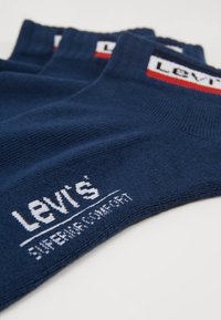 Sötétkék pamut zoknik, texturált anyaggal, fehér "Levi's" logóval és piros díszcsíkkal a szegélyen.