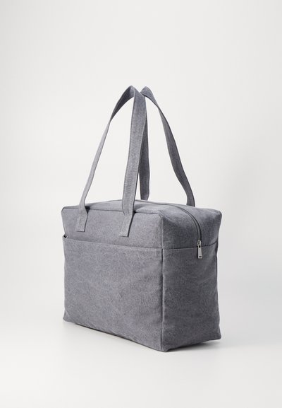 Saco de tecido cinza em forma retangular, com duas alças longas e fecho em zíper. Apresenta um material texturizado e um design simples.
