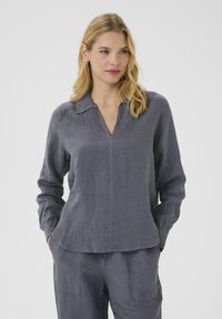 Blouse en lin gris avec un col, des manches longues, un décolleté en V, un détail de couture à l'avant et une coupe décontractée. Texture lisse et design décontracté.