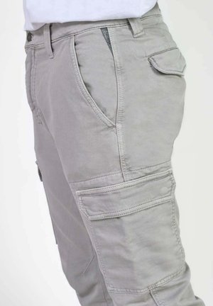 Pantalons cargo gris clair en mélange de coton, dotés de poches latérales, de coutures renforcées et d'une coupe confortable. Détail de fermeture éclair à l'avant visible.