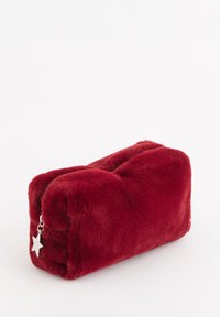 Rød rektangulær pude i plysstof med blød tekstur, med en sølvstjerne som lynlåstrækker på den ene side. Kompakt og glat overflade.