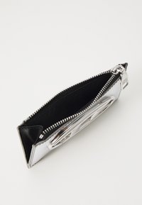 Metallic silver wallet with black accents, zip closure, smooth texture, and a logo detail. Inside features a black fabric lining.