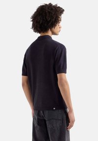 Korte mouwen marineblauw poloshirt van gladde stof, met een ribbelkraag, zichtbare stiksels en een klein merketiket aan de zoom.