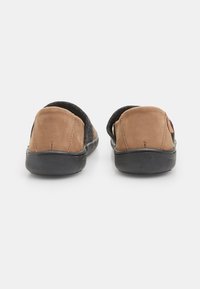Parte trasera de ante marrón, parte superior de tela negra, diseño tipo slip-on, costuras en contraste y suela de goma para mayor durabilidad. Sin patrones o acentos visibles.