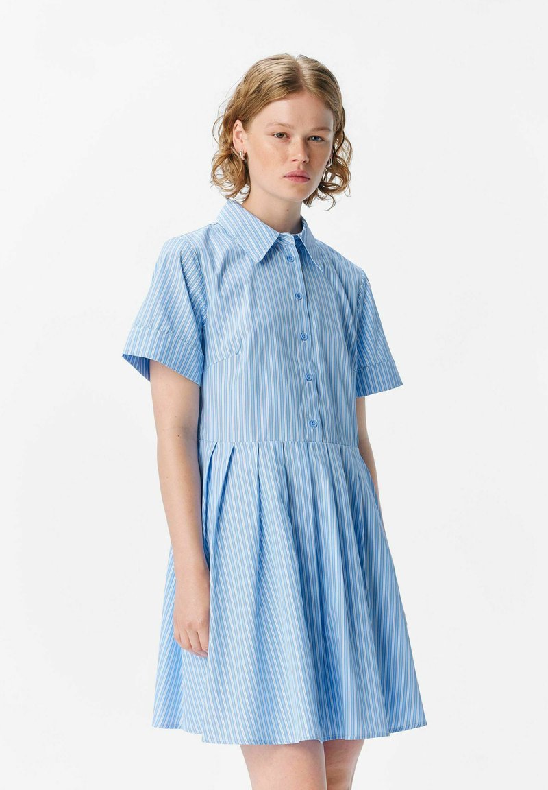 Robe courte à manches courtes rayée bleue avec un devant à boutons, un col, et une jupe en forme de A. Fabriquée en tissu léger avec des rayures verticales de différentes largeurs.