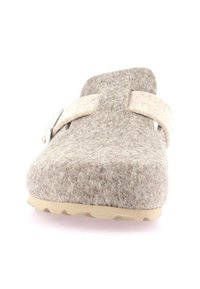Pantofole di feltro marroni dalla forma arrotondata, con una morbida fascetta beige e una suola in gomma beige. Nessun motivo visibile o hardware aggiuntivo.