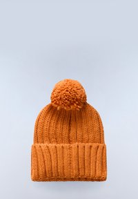 Oranžová pletená čepice s bambulí na vrchu, s žebrovanou texturou a ohrnutým lemem. Měkký, silný příze.