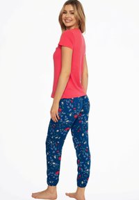 Red short-sleeve top paired with blue floral-patterned pants. The pants feature a mix of red, white, and blue flowers on a dark background.