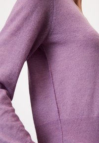 Lavendeltröja med en mjuk stickad textur, med långa ärmar och en figursydd design. Sömdetalj löper längs sidan.