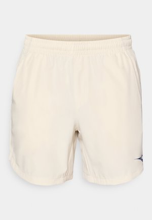 Shorts de bain beige clair avec une ceinture élastique, texture lisse, poches latérales et un accent de logo bleu marine en bas à gauche.