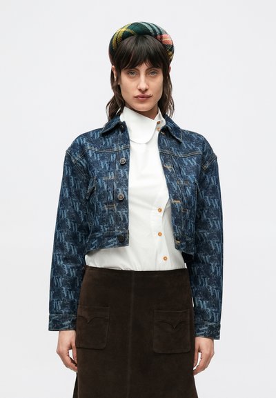 Cropped denim jacket in dark blue with a floral pattern, featuring button closures and a classic collar, paired with a white shirt and brown skirt.