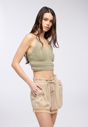 Top corto verde all'uncinetto, design a V, tessuto testurizzato. Pantaloni corti beige con vita elastica, tasche e bordo in pizzo sull'orlo.