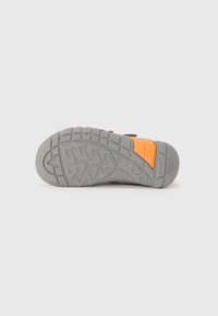 Semelle de chaussure en caoutchouc gris avec un motif de semelle texturé, comportant un accent orange et le texte "superfit 25" sur le côté.