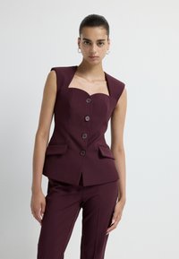Abito tailored bordeaux con scollo quadrato, maniche corte, cinque bottoni e tasche laterali; tessuto strutturato con una consistenza liscia.