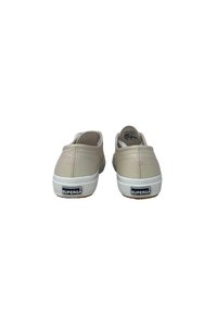 Scarpe slip-on beige con una sottile lucentezza, suola in gomma bianca e motivi testurizzati sul retro. Presenta un'etichetta di marca sul tallone.