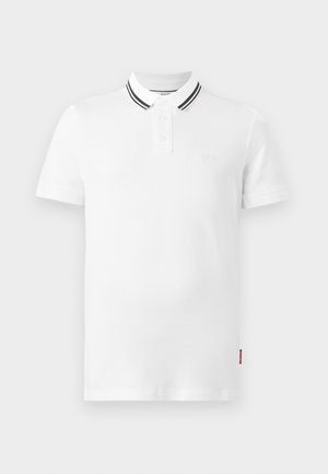 Λευκό πόλο μπλουζάκι με κοντά μανίκια, δύο κουμπιά στη λαιμόκοψη και διπλές μαύρες ρίγες στο γιακά, εμφανιζόμενο σε ανοιχτό γκρι φόντο.