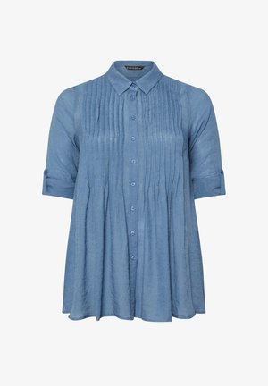 Chemise bleu clair à manches longues en tissu texturé, dotée de plis verticaux, d'un col et de manches retroussées.