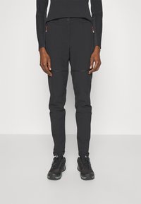 Black outdoor pants with a slim fit, featuring zippered pockets and contrasting seam accents. Paired with black athletic shoes.