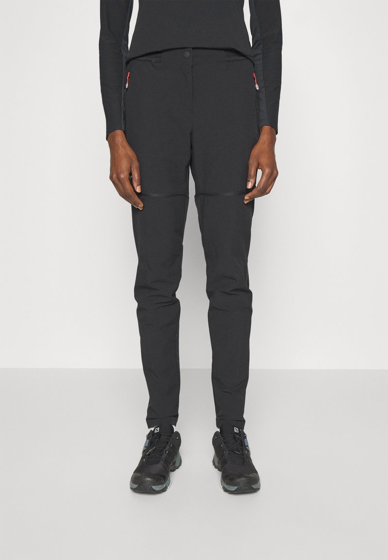 Black outdoor pants with a slim fit, featuring zippered pockets and contrasting seam accents. Paired with black athletic shoes.