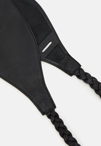 Zwarte leren accessoire met een gladde textuur en matte afwerking. Beschikt over een gevlochten band en een platte, langwerpige vorm met een sleuf voor een pasje.