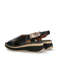 Sandalias de cuero negro con tiras cruzadas, correa de talón ajustable y suela de cuña con un acento beige. Detalle de hardware texturizado en oro.