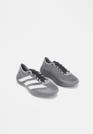 Paire de chaussures de sport grises et noires avec des bandes blanches et des lacets noirs sur fond blanc uni.