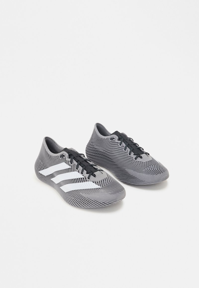 Paire de chaussures de sport grises et noires avec des bandes blanches et des lacets noirs sur fond blanc uni.