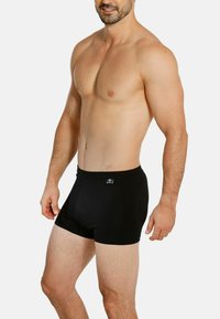 Black boxer briefs made from soft fabric, featuring a snug fit, elastic waistband, and minimalistic design without patterns or accents.