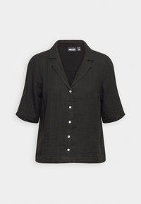 Chemise noire à manches courtes avec col, en tissu doux et texturé, dotée de six boutons blancs sur le devant.