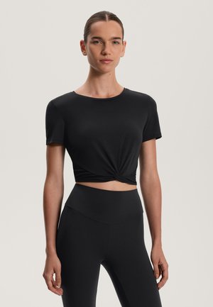 Black cropped t-shirt in soft, stretchy fabric with short sleeves and a twisted front detail, paired with high-waisted black leggings.