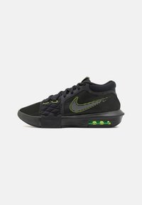 Scarpa da tennis nera Nike con accenti verde neon, cuscinetto d'aria visibile nella suola, parte superiore in tessuto a rete e trapuntato, e lacci neri.