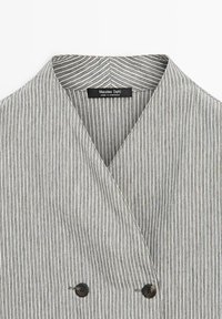 Graue und weiße gestreifte Jacke mit doppelreihigem Design, schwarzen Knöpfen und einem gekerbten Kragen. Das Etikett trägt die Aufschrift "Massimo Dutti, Hergestellt in Marokko."