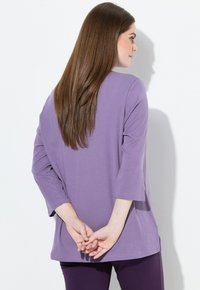 Top lavanda a maniche lunghe con maniche ampie e vestibilità rilassata, abbinato a pantaloni viola scuro. Tessuto morbido, design senza cuciture, adatto per un abbigliamento casual.