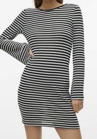 Robe à rayures noires et blanches avec manches longues, col rond et silhouette ajustée. Le tissu a une texture lisse avec des rayures fines et ondulées.