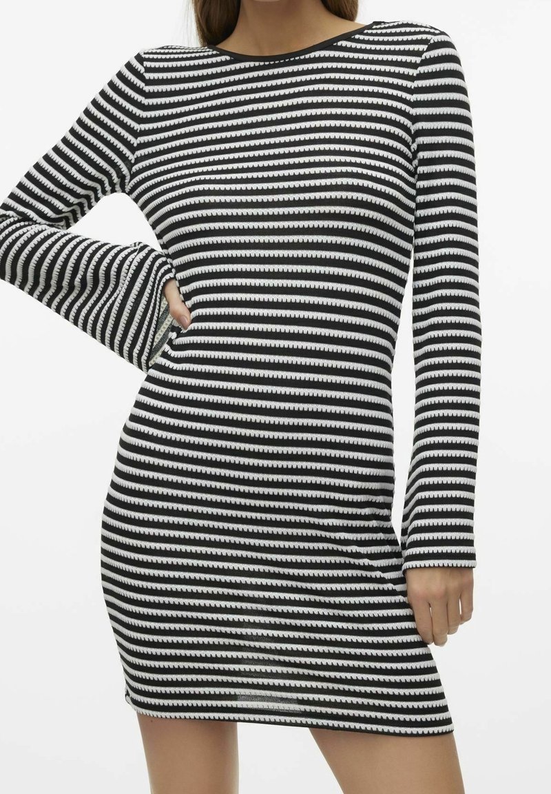 Robe à rayures noires et blanches avec manches longues, col rond et silhouette ajustée. Le tissu a une texture lisse avec des rayures fines et ondulées.