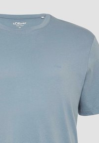 Lichtblauwe katoenen T-shirt met ronde hals en korte mouwen. Bevat een klein geborduurd logo op de borst. Gladde textuur.
