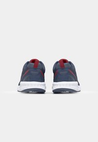 Sport shoes in navy blue with red accents. Slip-on design with a textured fabric upper and a white rubber sole. Labeled with "Kappa."