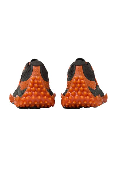 Paar schwarze und orangefarbene Turnschuhe, von hinten betrachtet, mit strukturierten orangenen Sohlen mit erhöhten runden Griffen und Oberteilen aus Maschengewebe.